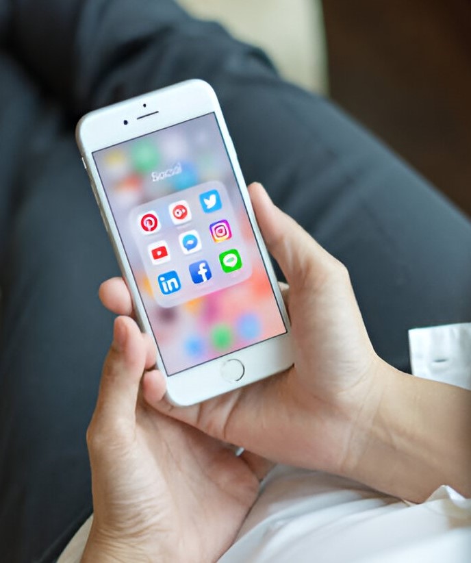 Businesswoman holding iPhone smartphone with on-screen social media icons as Internet technology